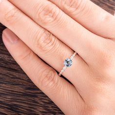 a woman's hand holding an engagement ring with a blue topazte on it