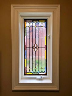 a stained glass window in the corner of a room with brown walls and white trim