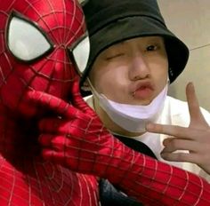 a man in a spiderman costume is making the peace sign with his hand while wearing a mask