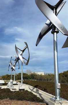 several metal sculptures on the side of a road in front of a blue sky with clouds