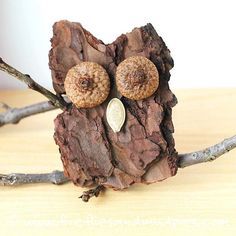 an owl made out of wood sitting on top of a wooden table next to some branches