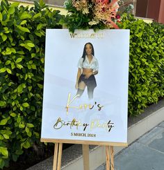 a sign with a woman's birthday photo on it in front of some bushes