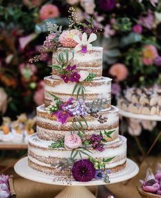 a multi layer cake with flowers and leaves on the top is surrounded by other desserts