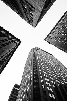 black and white photograph of tall buildings in new york city, looking up at the sky