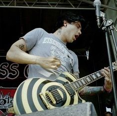 a man playing an electric guitar in front of a microphone at a music festival or concert