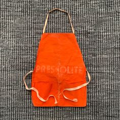 an orange apron sitting on top of a carpet