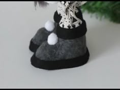 a small doll is sitting on top of a rock next to a christmas tree with white pom - poms