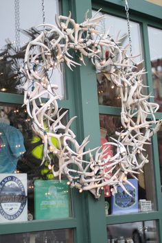 a wreath made out of antlers hanging from the side of a store front window