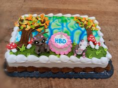 a birthday cake with an animal theme on it sitting on a wooden table in front of a tree