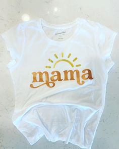 "This Mama  shirt is perfect to wear to match your \"First Trip Around The Sun\" or even just to show your true Sunshine self! Made with our no shed glitter its sure to be a hit. Shirt: Cotton Washing: Turn inside out and wash on cold !!Don't forget to follow us on Facebook and Instagram!!" Gold T-shirt With Letter Print For Summer, Spring Gold Graphic Print T-shirt, Gold Letter Print Top For Summer, Gold Letter Print Tops For Summer, Gold Cotton Tops With Logo Print, Gold Graphic Tee Tops For Summer, Gold Short Sleeve Top With Text Print, White Relaxed Fit Top For Birthday, Spring Birthday Tops With Text Print