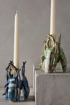 two candles sitting next to each other on top of a block of concrete with one candle in the middle