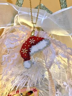 a christmas ornament hanging from the side of a white wreath on top of a table