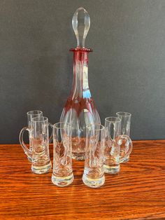 a glass pitcher and six glasses on a wooden table