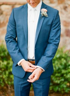 a man in a blue suit and white shirt is holding his hand on his lapel