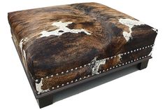 a cow hide ottoman with studded legs