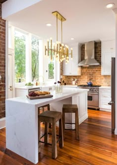 a kitchen with an island and two stools in front of the counter top that matches the brick wall