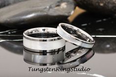 two wedding rings sitting next to each other on top of a black and white table