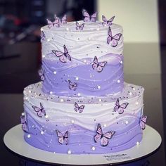 there is a three layer cake with purple butterflies on the frosting and icing