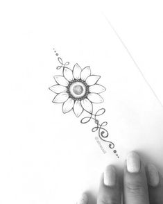 a woman's hand holding a piece of paper with a drawing of a sunflower on it