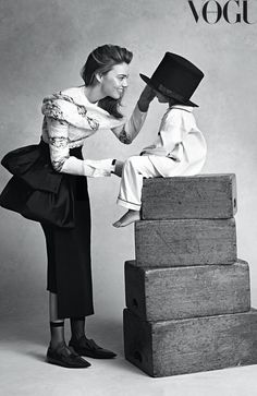 two women in dresses and hats are playing with each other on top of wooden blocks