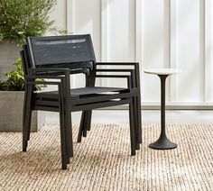 two black chairs sitting on top of a rug next to a table and potted plant