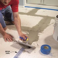 a man is working on the floor with tape and a squirt in his hand