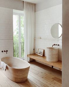 a bathtub sitting on top of a wooden floor next to a sink and window