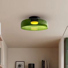 a green lamp hanging from the ceiling in a room with bookshelves and pictures on the wall