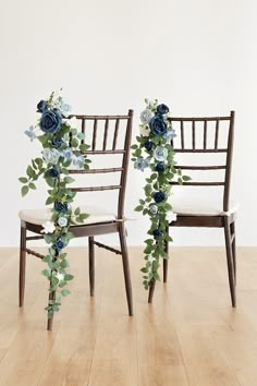 two chairs decorated with blue flowers and greenery