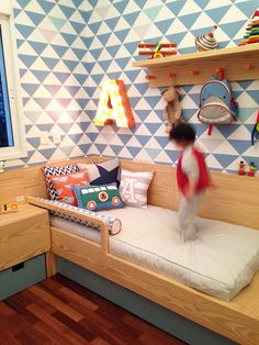 a child's bedroom with blue and white wallpaper, wooden furniture and shelves