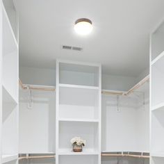 an empty walk in closet with white shelves