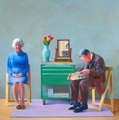 an older man and woman sitting on chairs in front of a green dresser with flowers