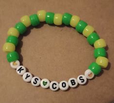 a green and yellow beaded bracelet with the word yescobs written on it