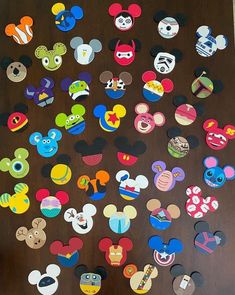 mickey mouse magnets are arranged on a wooden surface with the faces of many different disney characters