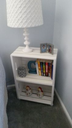 a white book shelf with books on it and a lamp in the corner next to it