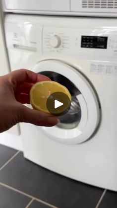 a person holding an orange in front of a washing machine