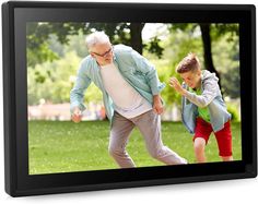 an old man and young boy playing with a soccer ball in the park on a black frame