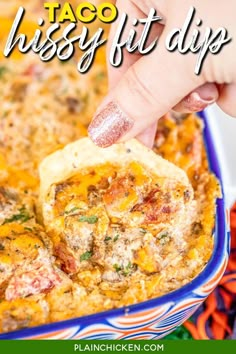 a hand dipping a tortilla chip into a casserole in a blue dish