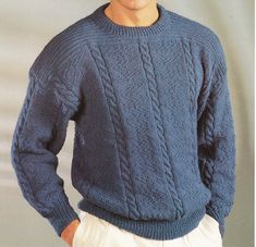 a young man wearing a blue sweater and white pants with his hands in his pockets