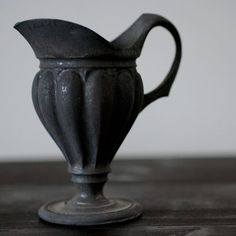 a black vase sitting on top of a wooden table