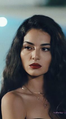 a woman with long dark hair wearing a black strapless top and red lipstick on her lips