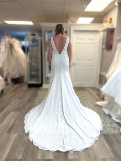 a woman in a white wedding dress looking at dresses