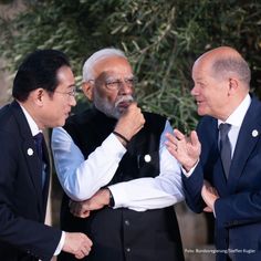 three men standing next to each other with one holding his hand on the other's chest