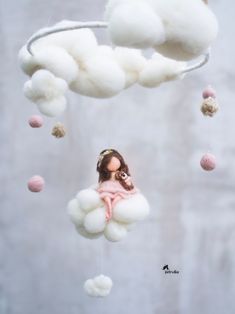 a doll is sitting on a cloud mobile