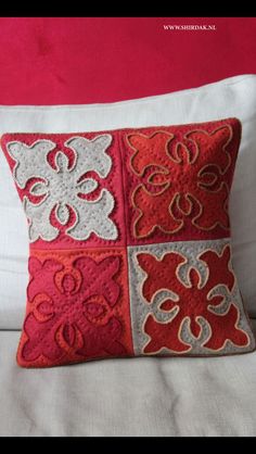 a red and white pillow sitting on top of a bed