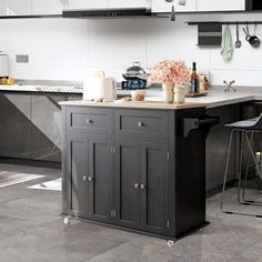 a kitchen with black and white cabinets, an island in the middle and two stools at the end