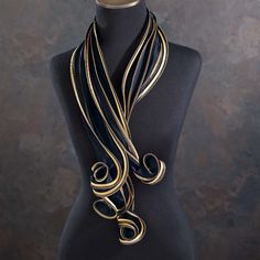 Our UK artisan, Tammy, takes inspiration from tropical forms to create this fashion-forward black and gold sculptural scarf. Handcrafted from silk satin and silk organza, this scarf combines rich gold and black hues for a bold look in a classic colorway. The unique, twisting shape makes this a bold statement piece. Handcrafted for Uno Alla Volta, from the heart and hands of the artisan. Dimensions - Approx. 44'' long. Organza Scarf, Gold Scarf, Character Clothing, Murano Glass Necklaces, Murano Glass Jewelry, Scarf Silk, Wire Necklace, Gold Silk, Exclusive Jewelry