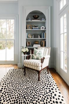 a living room filled with furniture and bookshelves on top of a hard wood floor