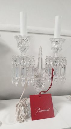 a small chandelier with three candles and a red tag hanging from it's side