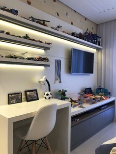 a room with a desk and shelves filled with toy cars on the wall above it